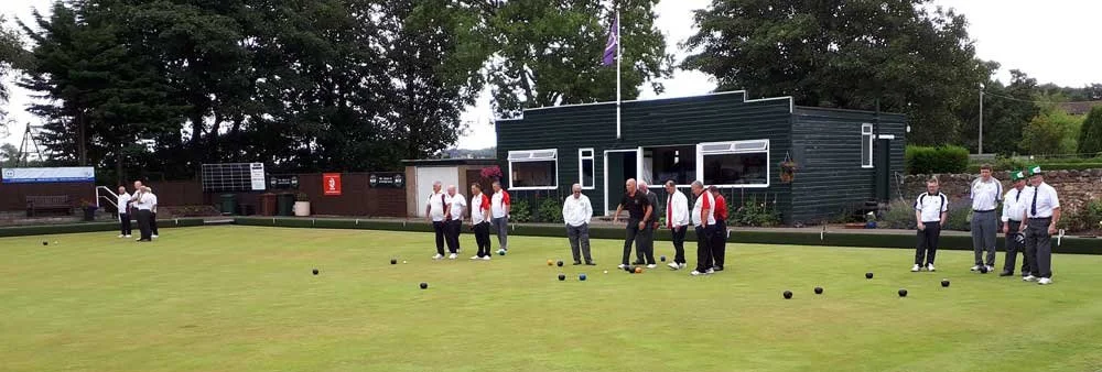 People playing lawn bowls on a green, with a building in the background.