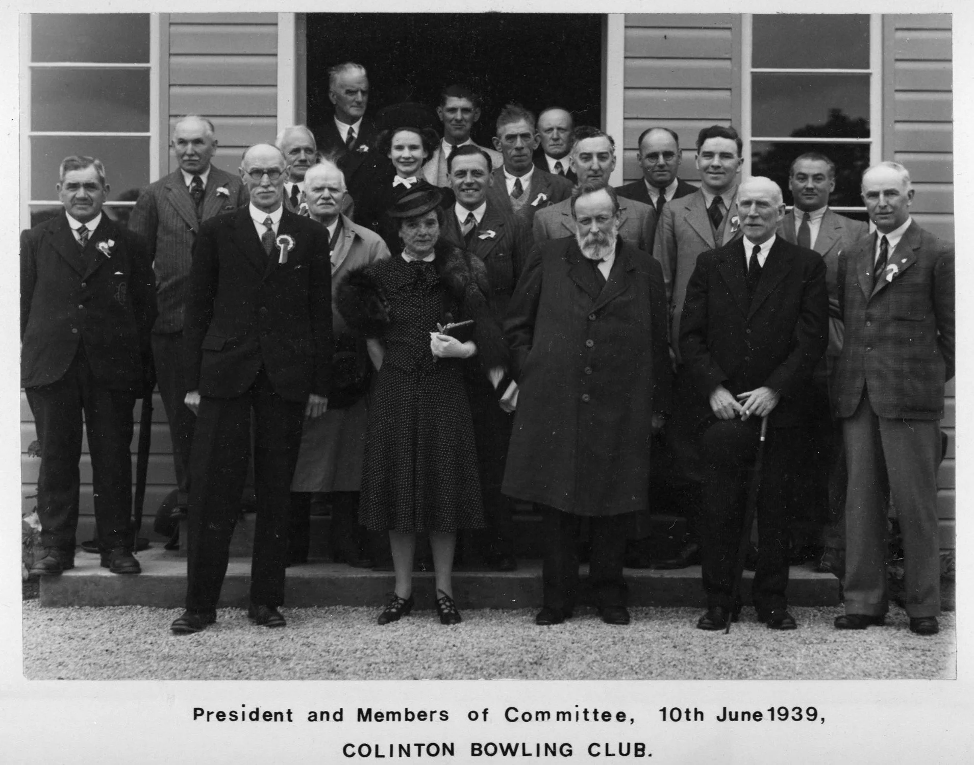 Black and white photograph of a group of men and women dressed in formal attire, standing on stairs in front of a building, with a caption below noting the date as June 10, 1939, and their association with the Clinton Bowling Club.