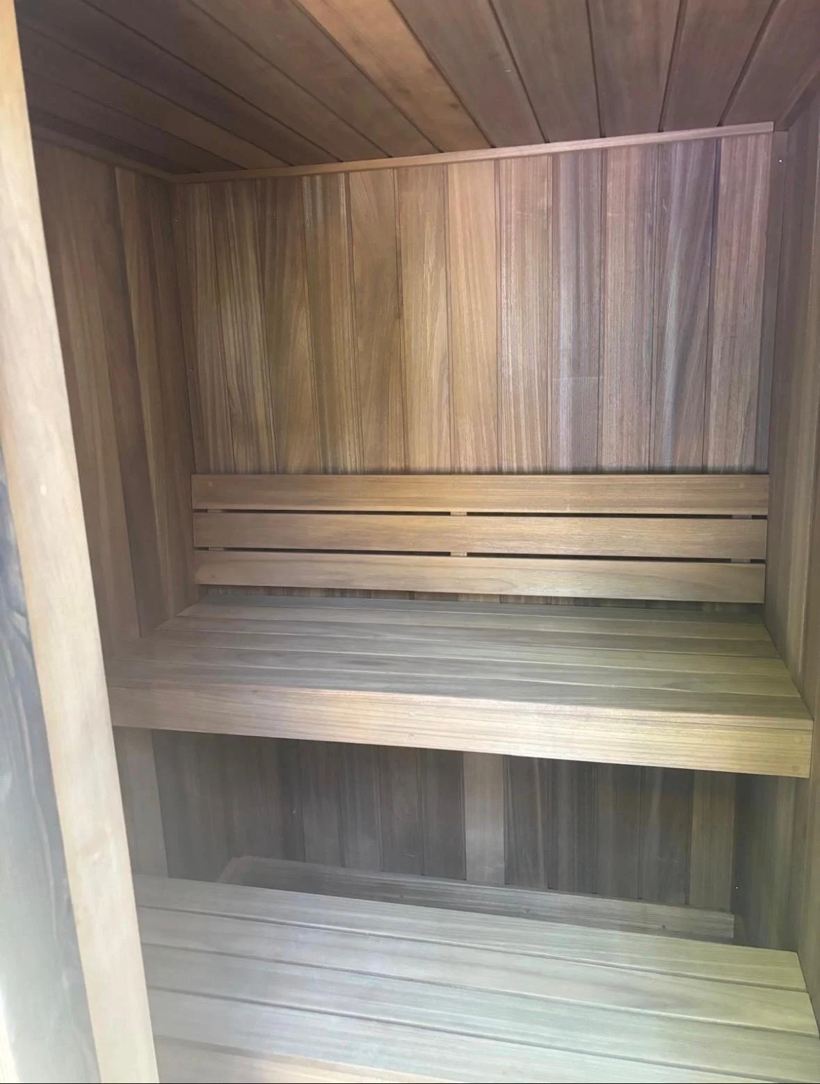 Interior of a wooden sauna with wooden walls, ceiling, and benches.