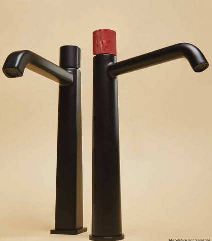 Modern black water faucets with a minimalist design, one with a red cap, set against a beige background.