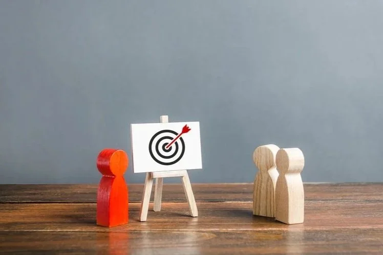 Strategie di prodotto e branding: piccolo bersaglio su cavalletto con pedine in legno che rappresentano il target aziendale.