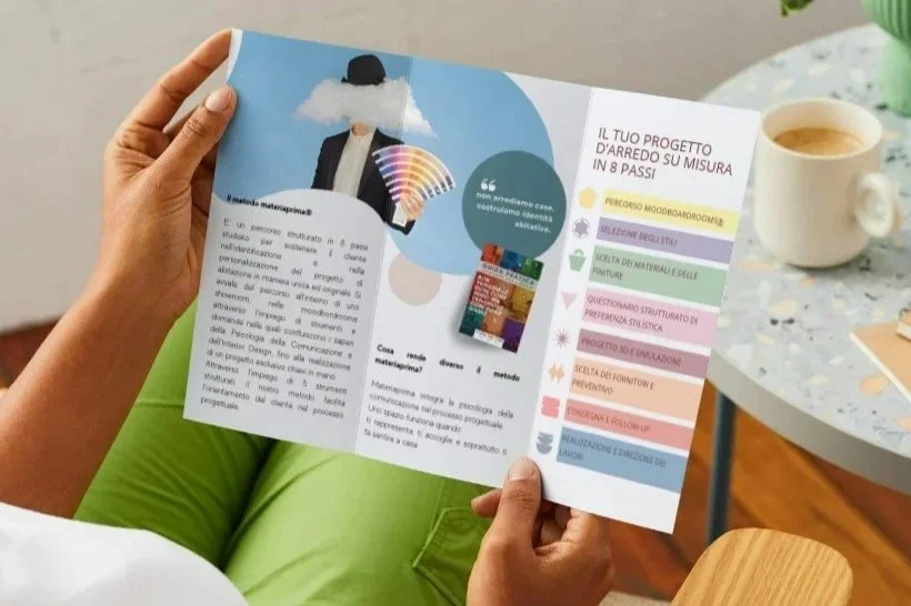 Progettazione di comunicazione visiva: persona che legge una brochure promozionale aziendale stampata a colori.