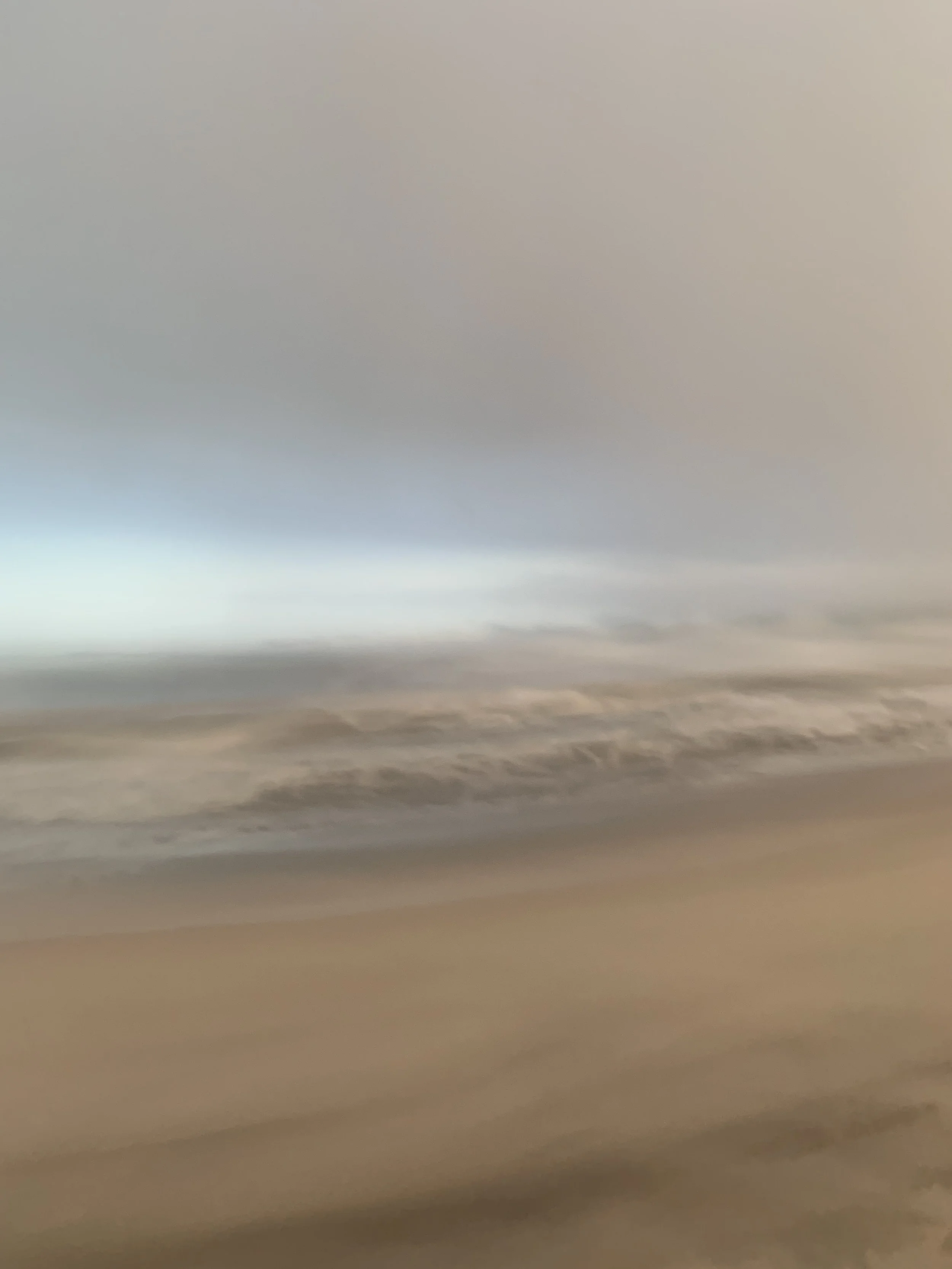 At the Edge of Light, Fire Island. A pale band of light at the horizon above brown sand and grey water.