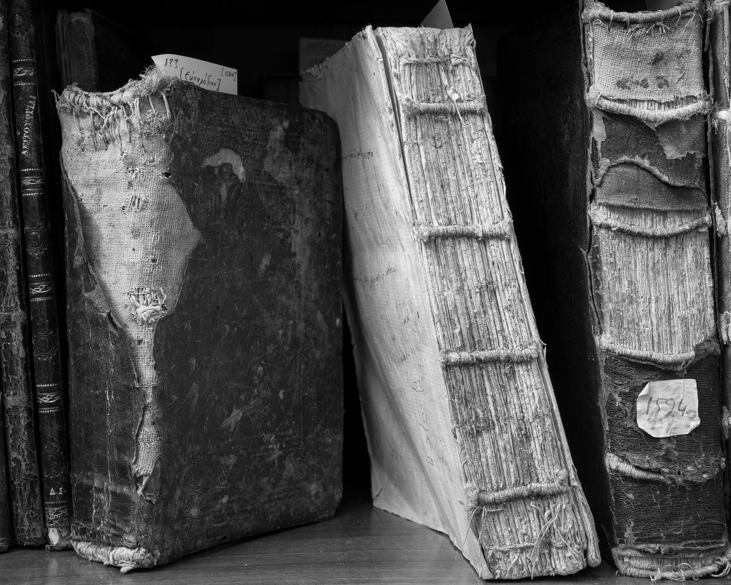 Harbour of the Soul. Falling in love. Three bound manuscripts leaning together on a shelf, one with its sewing cords exposed.