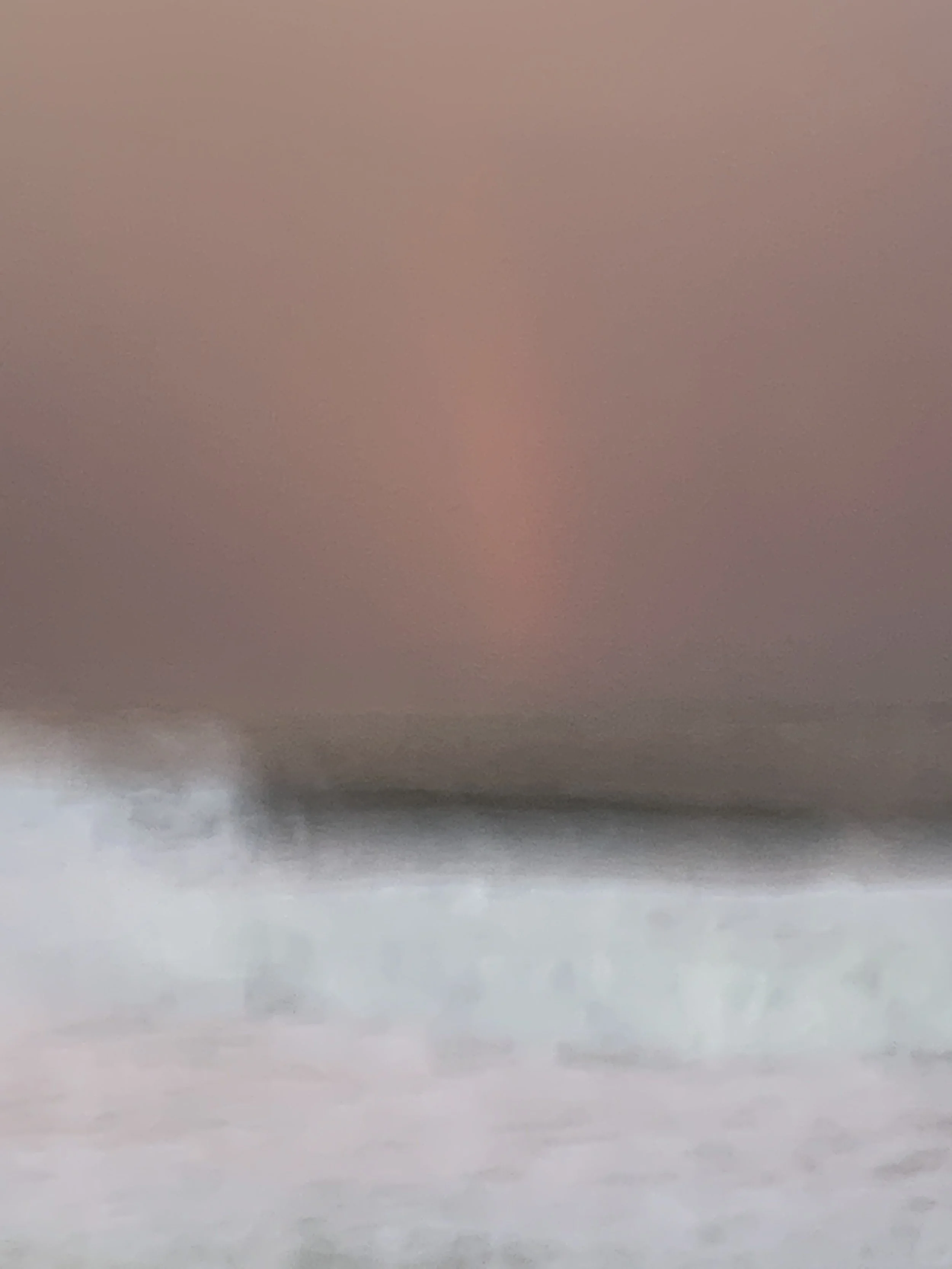 At the Edge of Light, Fire Island. A faint vertical glow in a mauve sky above the breaking line.