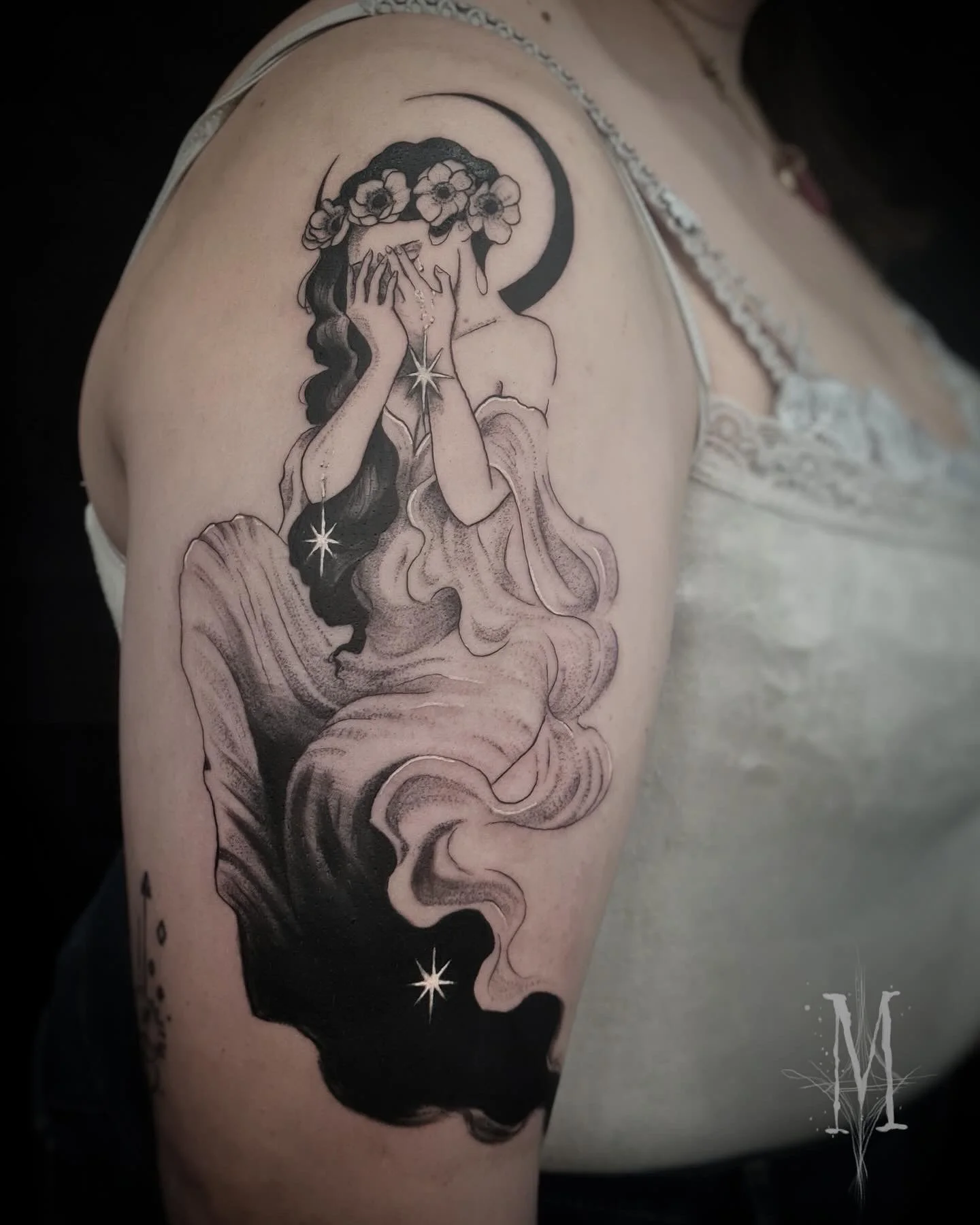 Tatouage d'une femme avec une couronne de fleurs, qui pleure ses 'étoiles, avec une lune en arrière-plan.
