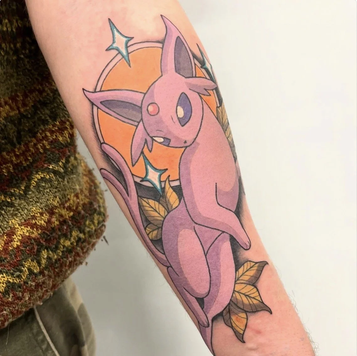 Tatouage d'un Pokémon Feunard avec un fond d'orange et des feuilles