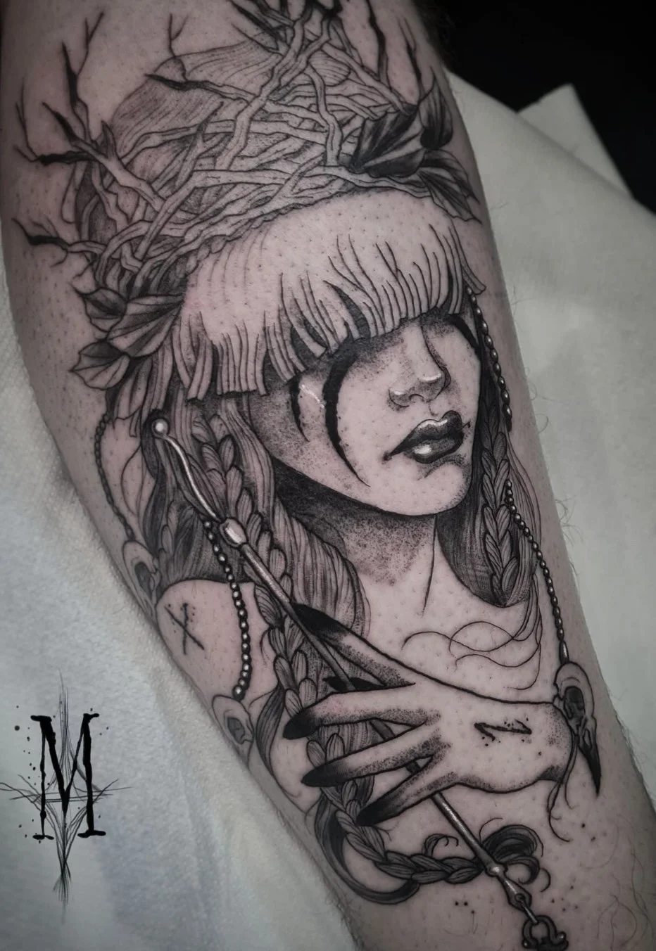 Tatouage d'une shaman viking avec des cheveux mi-longs, un bandeau sur les yeux  et une couronne de branches, tenant une flèche. Son visage est partiellement masqué par une cicatrice ou une marque noire. Style noir et gris, dessin détaillé.