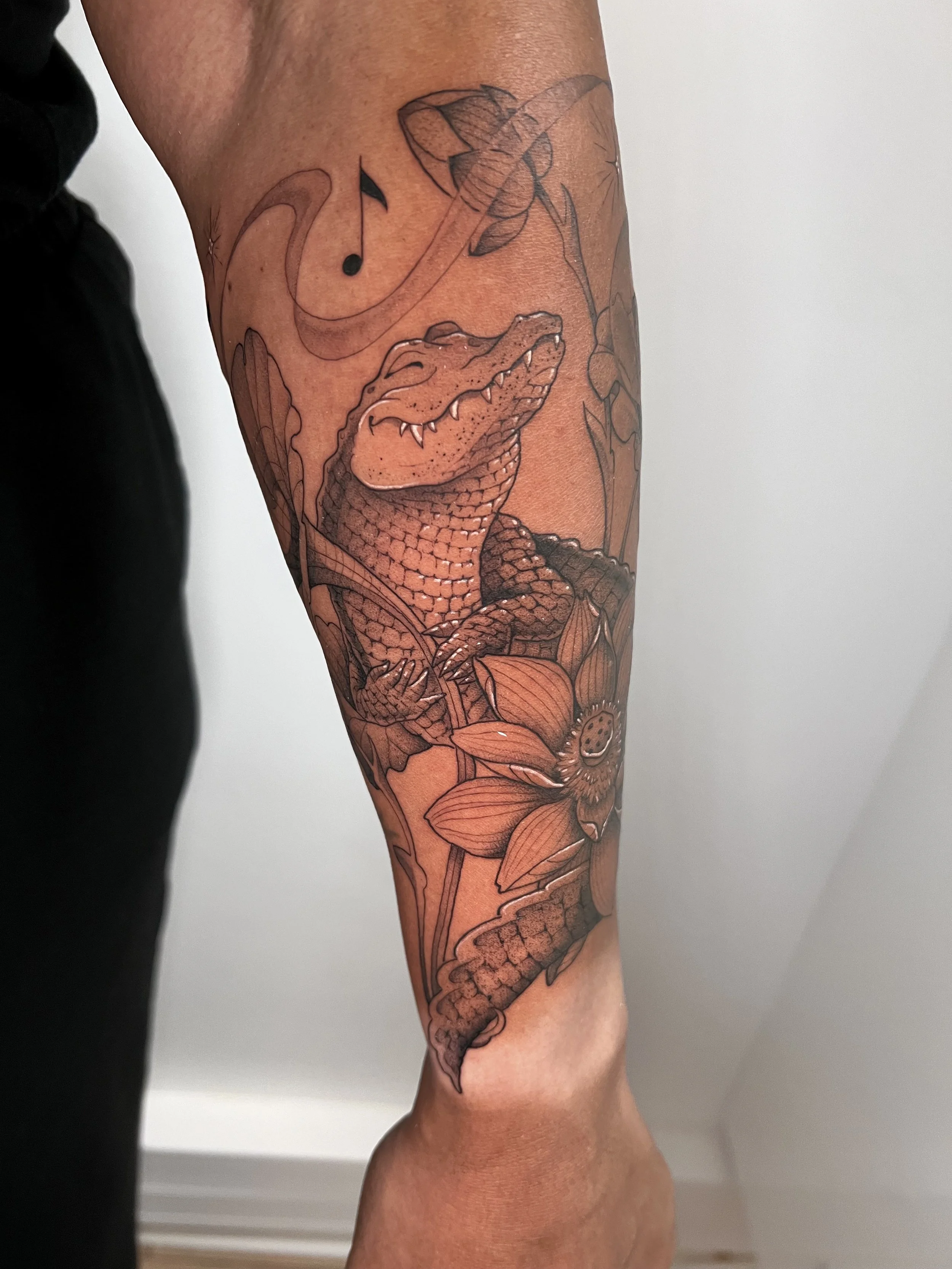 Tatouage d'un crocodile musicien sur le bras.