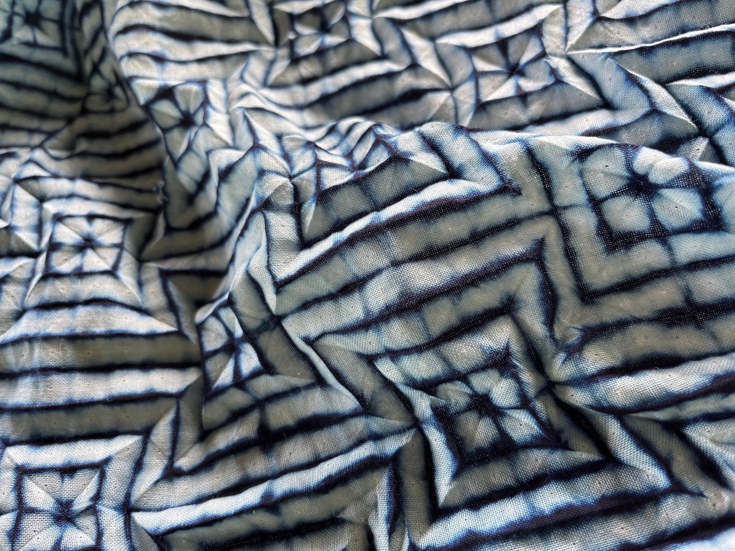 Tessuto realizzato con tecnica shibori con motivo geometrico a righe blu e bianche.