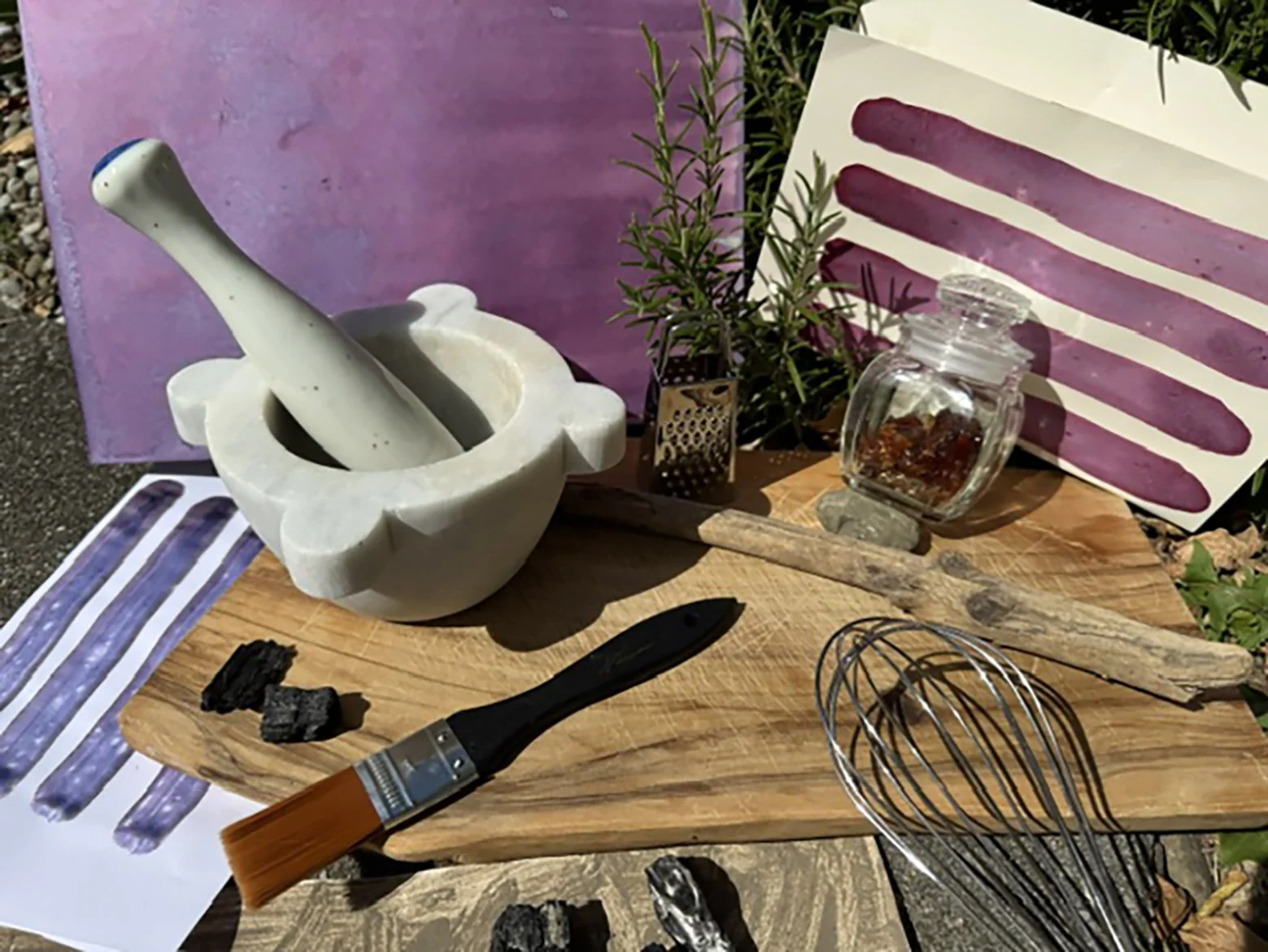 Utensilien auf einem Holztisch, darunter ein Schneebesen, eine Marmor-Mörser und ein Pinsel.