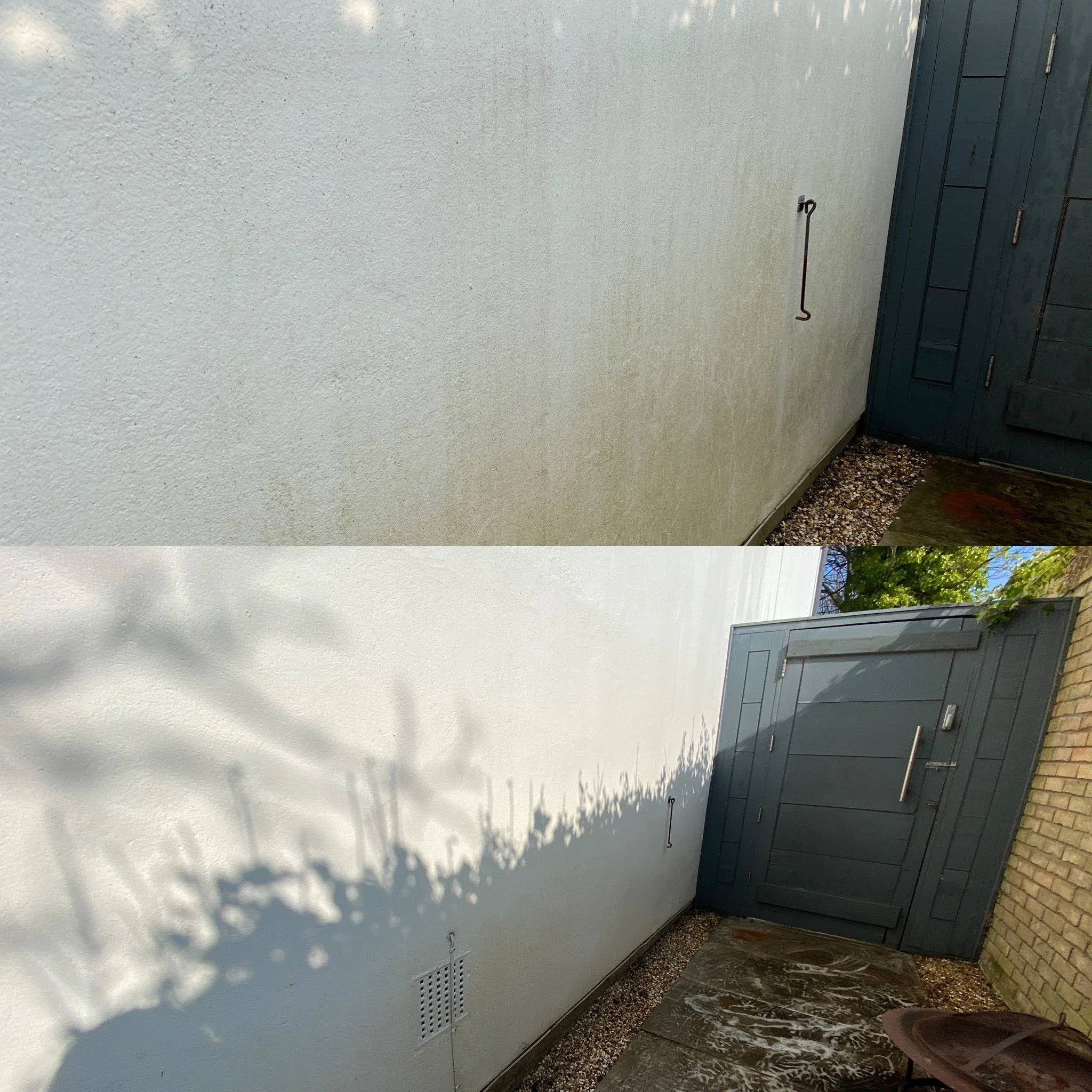 A white exterior wall of a building with a grey metal door and an outdoor hose holder. The ground is covered with gravel and a stone tile path. Shadows of tree branches are cast on the wall.