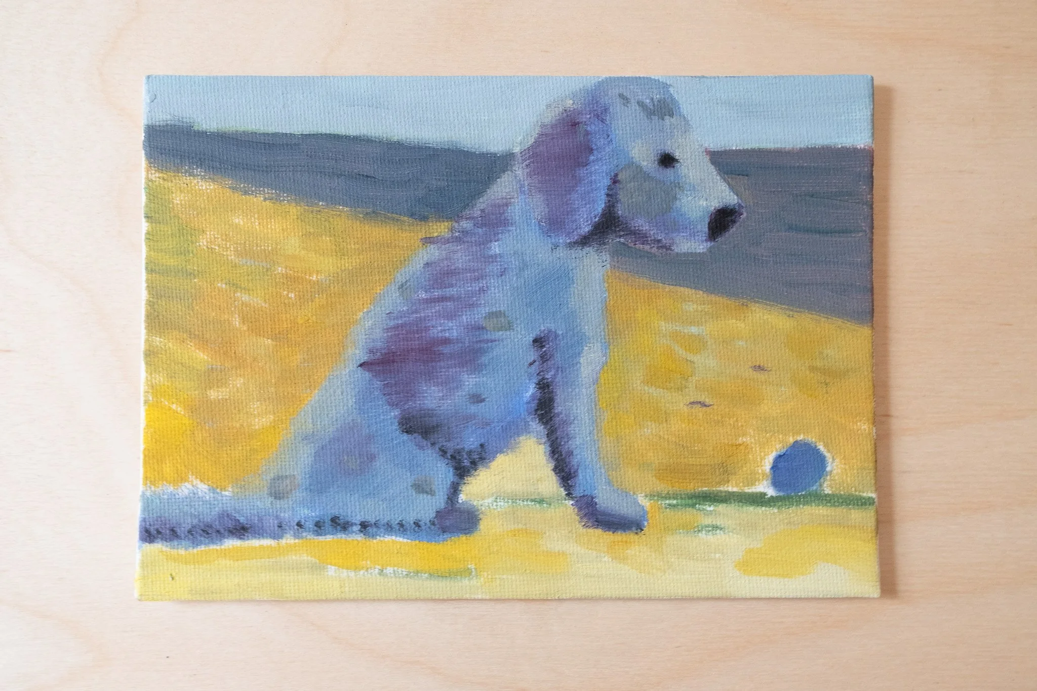 Small oil painting of a dog with bluish fur sitting languidly on a beach in front of a ball; the sky and the sea in the background are a similar blue..