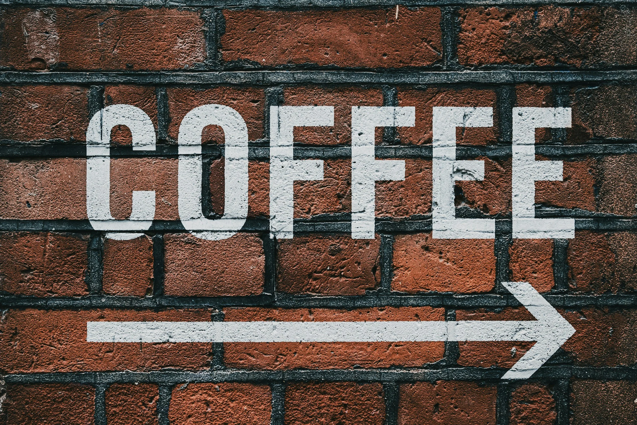 A brick wall with a painted white sign that reads 'OFFICE' and an arrow pointing to the right.