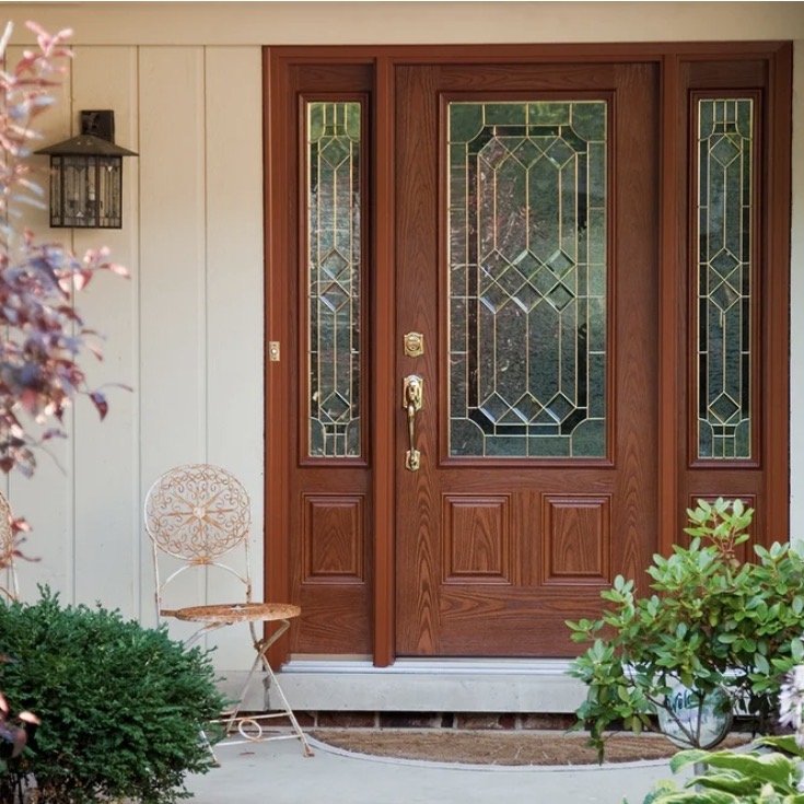 Front door with decorative glass panels, surrounded by plants and a small decorative chair.