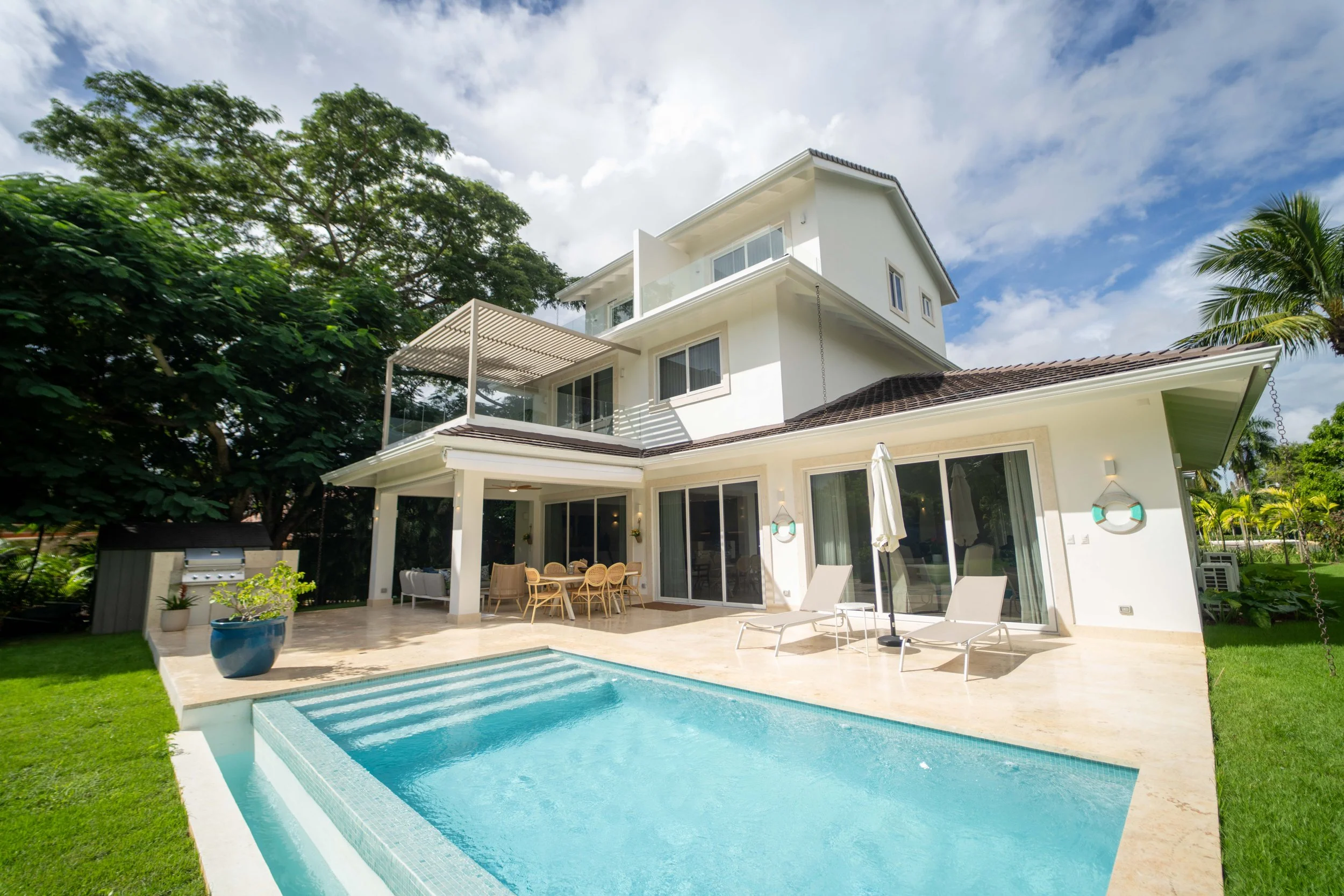 Completed private residence in Casa de Campo, Dominican Republic, sold by Yamilis de la Rosa and built by Constructora Caña Roja, featuring a pool, covered terrace, and landscaped outdoor living areas.