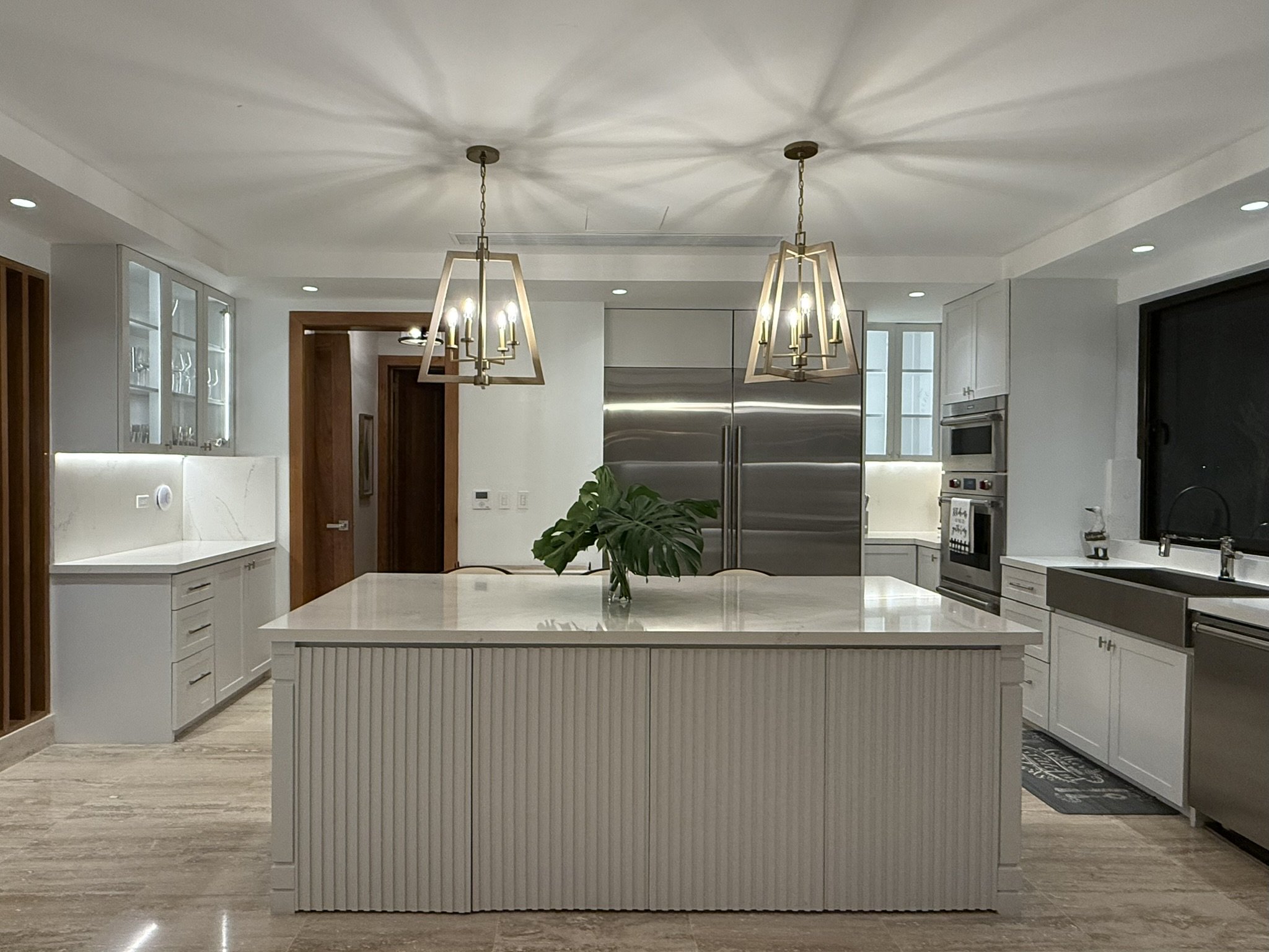 Completed private residence designed by Yamilis de la Rosa in Casa de Campo, Dominican Republic, featuring a spacious kitchen with a central island, custom cabinetry, and integrated lighting.