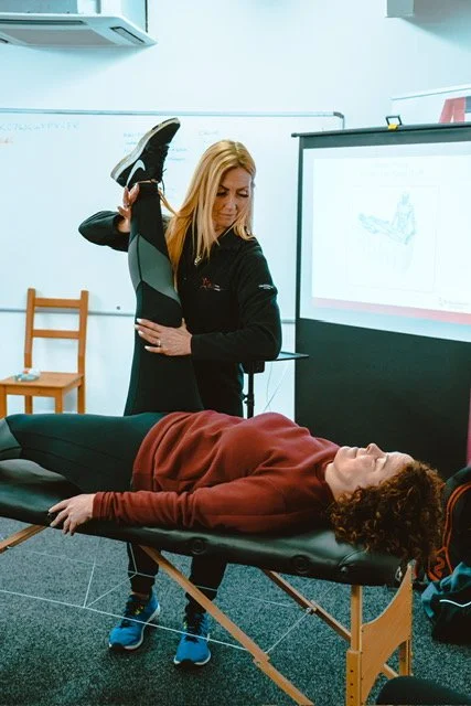 Biomechanics coach guiding a client’s leg movement during a screening