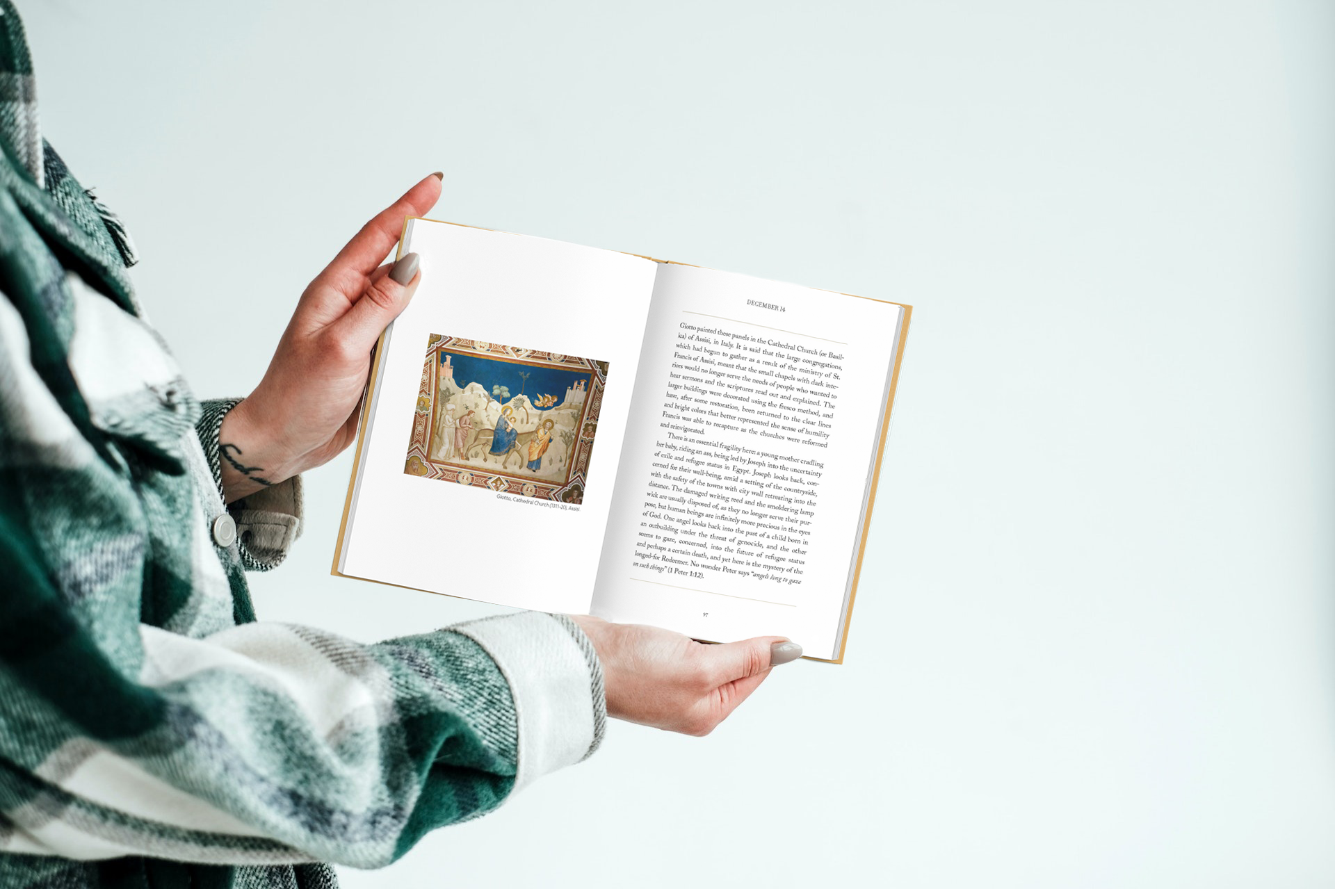 Hands holding Mary's Voice open at a spread showing a nativity painting beside the day's reflection