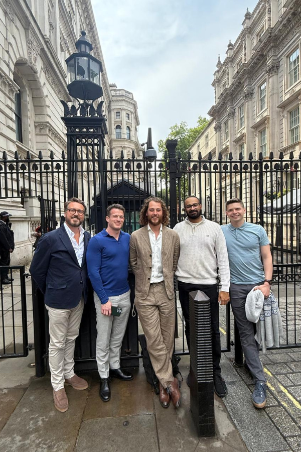 Mark McKenna CEO of VentureTech Partners standing outside of No. 10 Downing Street, With tThe Fenway Data team, with historic white buildings in the background.