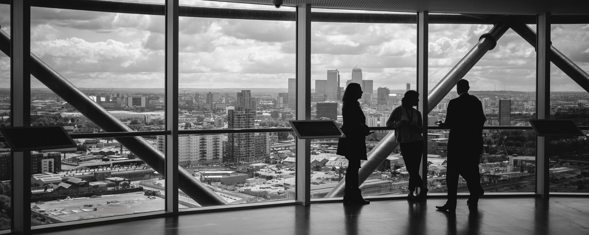 Silhouettes of three people talking in front of large windows overlooking a city skyline, with clouds in the sky. VentureTech Partners Limited hero image