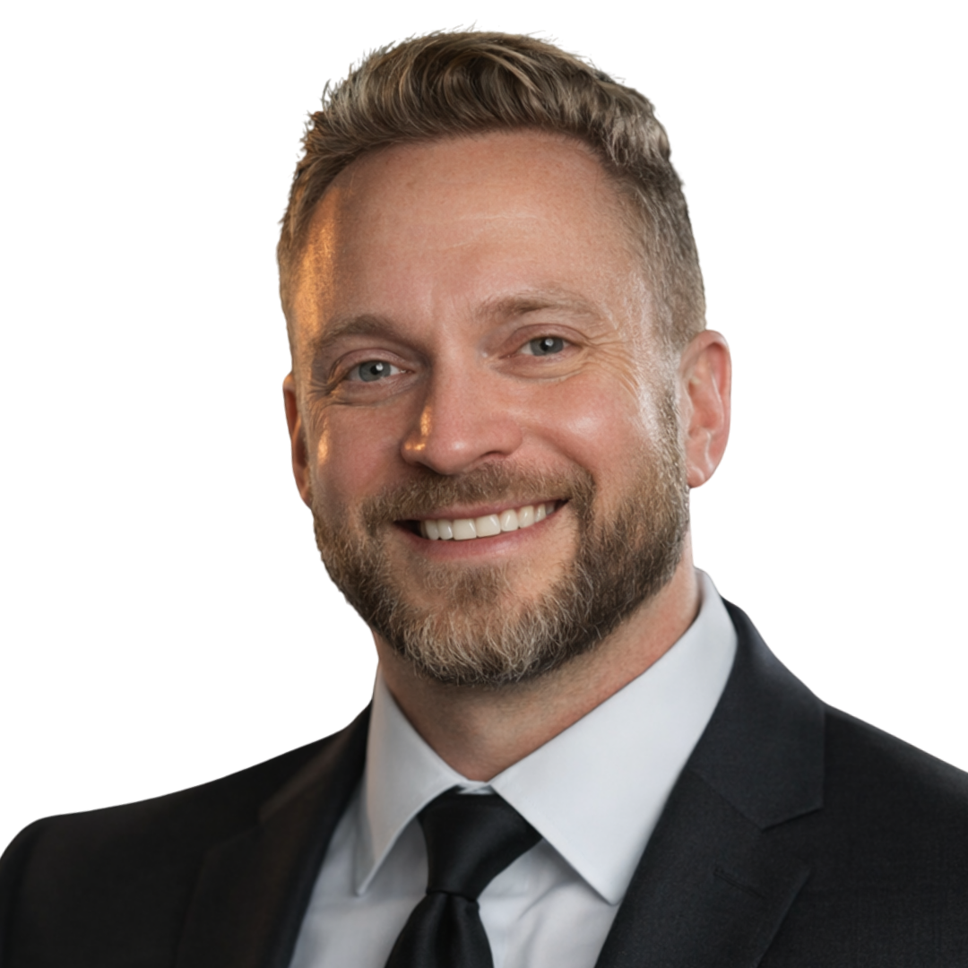 Headshot of a smiling man with short light brown hair and a beard, wearing a black suit, white shirt, and black tie.