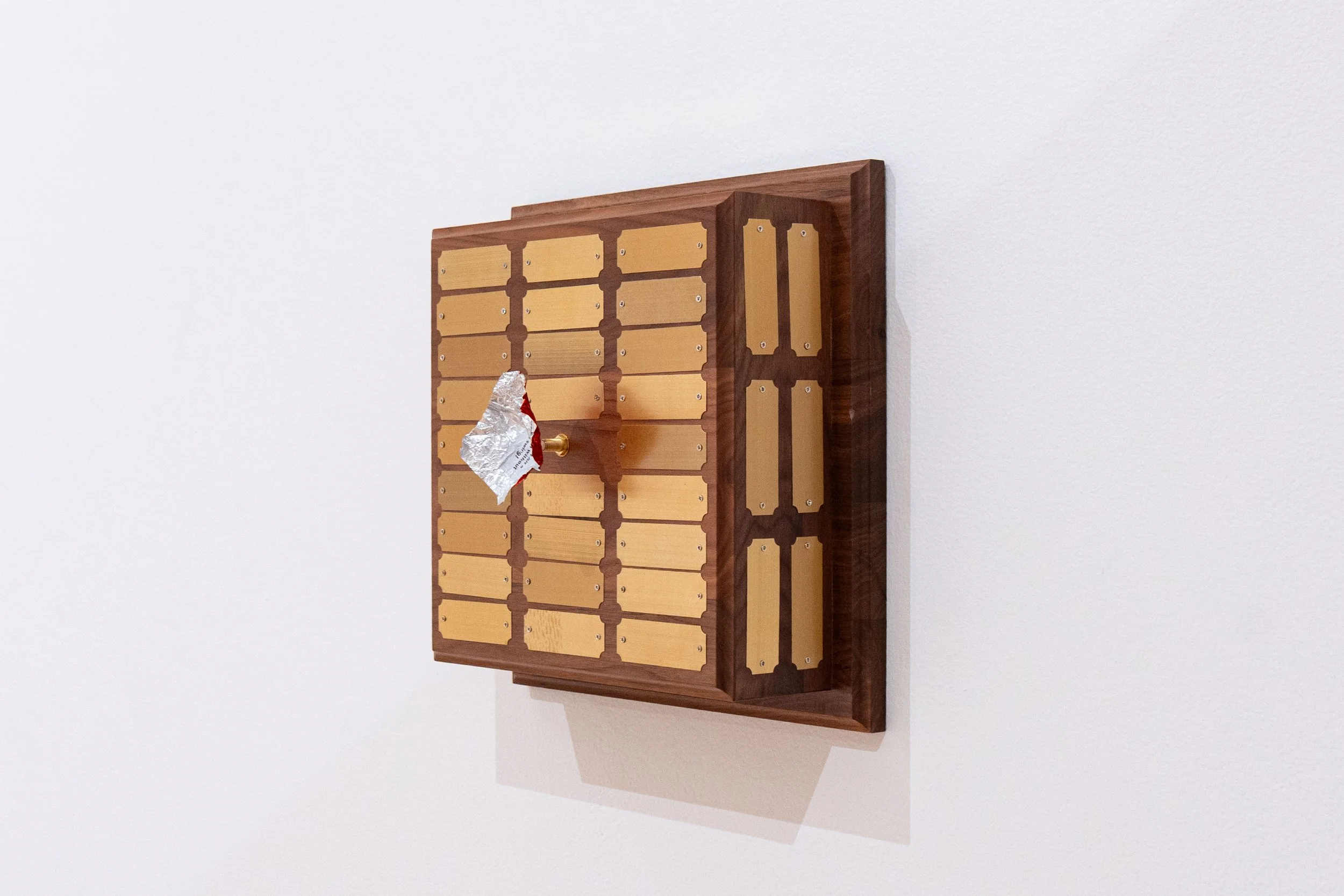   Untitled (Perpetual Plaque) —   Walnut, brass, clock movement, foil chocolate wrapper
 
Image courtesy of Priya Vaswani