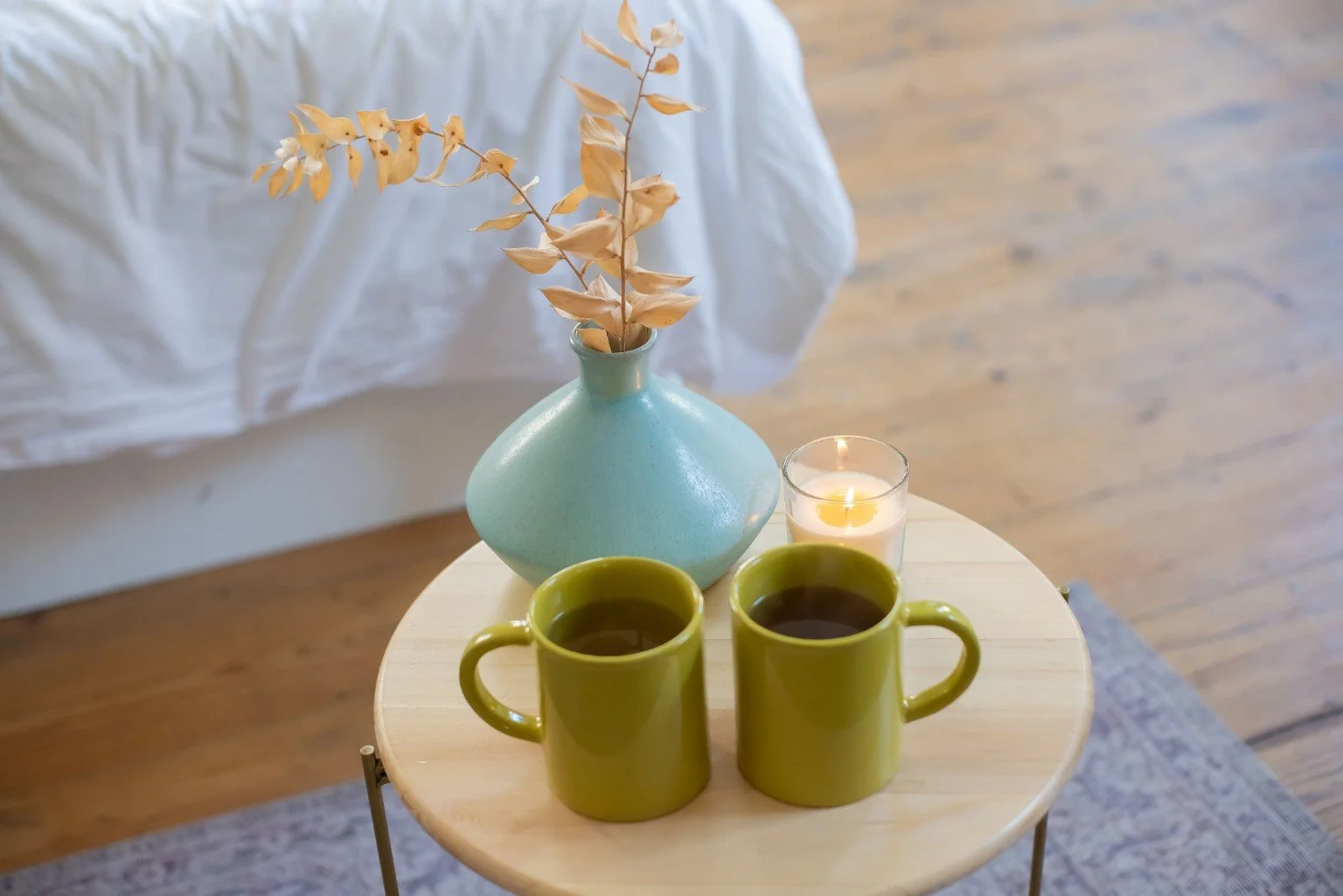 Two mugs beside a vase and candle, suggesting a relaxed conversation at home