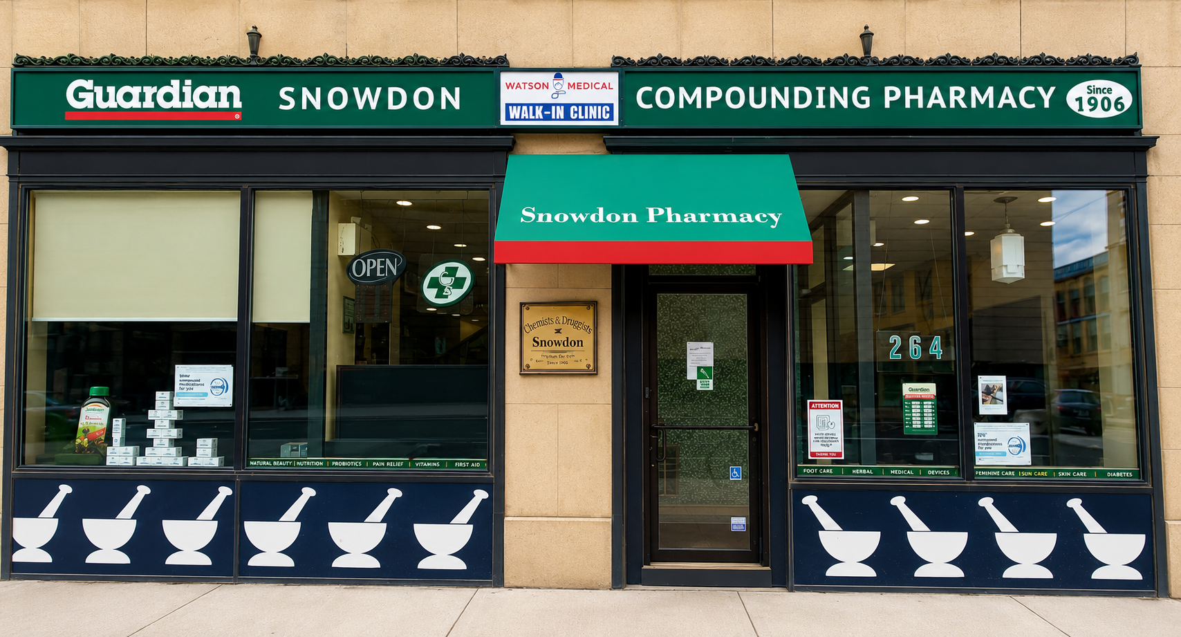 The storefront of Snowdon Pharmacy with green signage, large windows, and a red-and-green awning. The signs indicate it is a compound pharmacy established in 1906. The window displays various health products and signs, with a door marked with a pharmacy symbol and an open sign.
