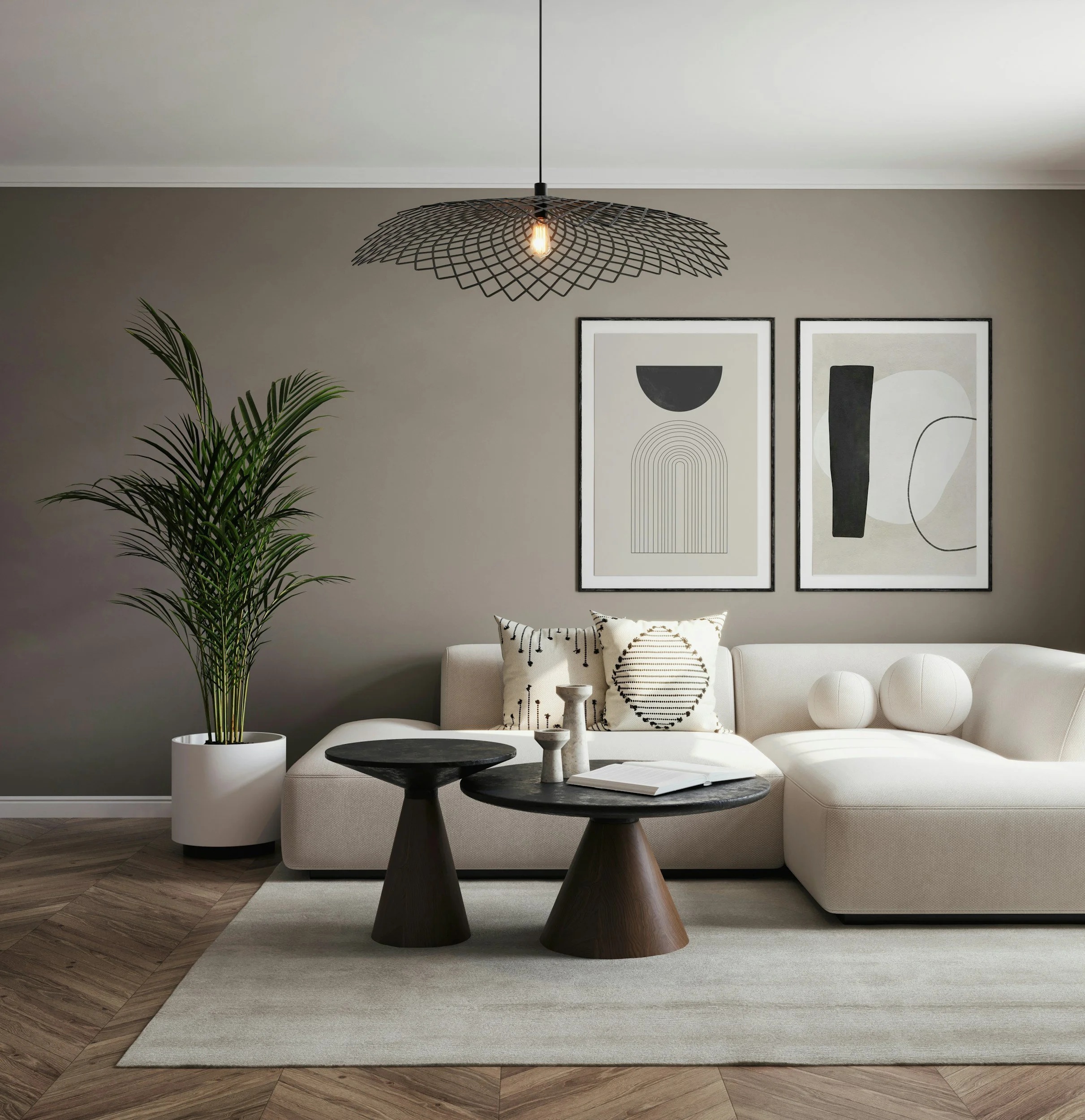 Living room with beige sofa, black and white abstract framed art, patterned pillows, wooden flooring, potted plant, and a modern black wire pendant light.