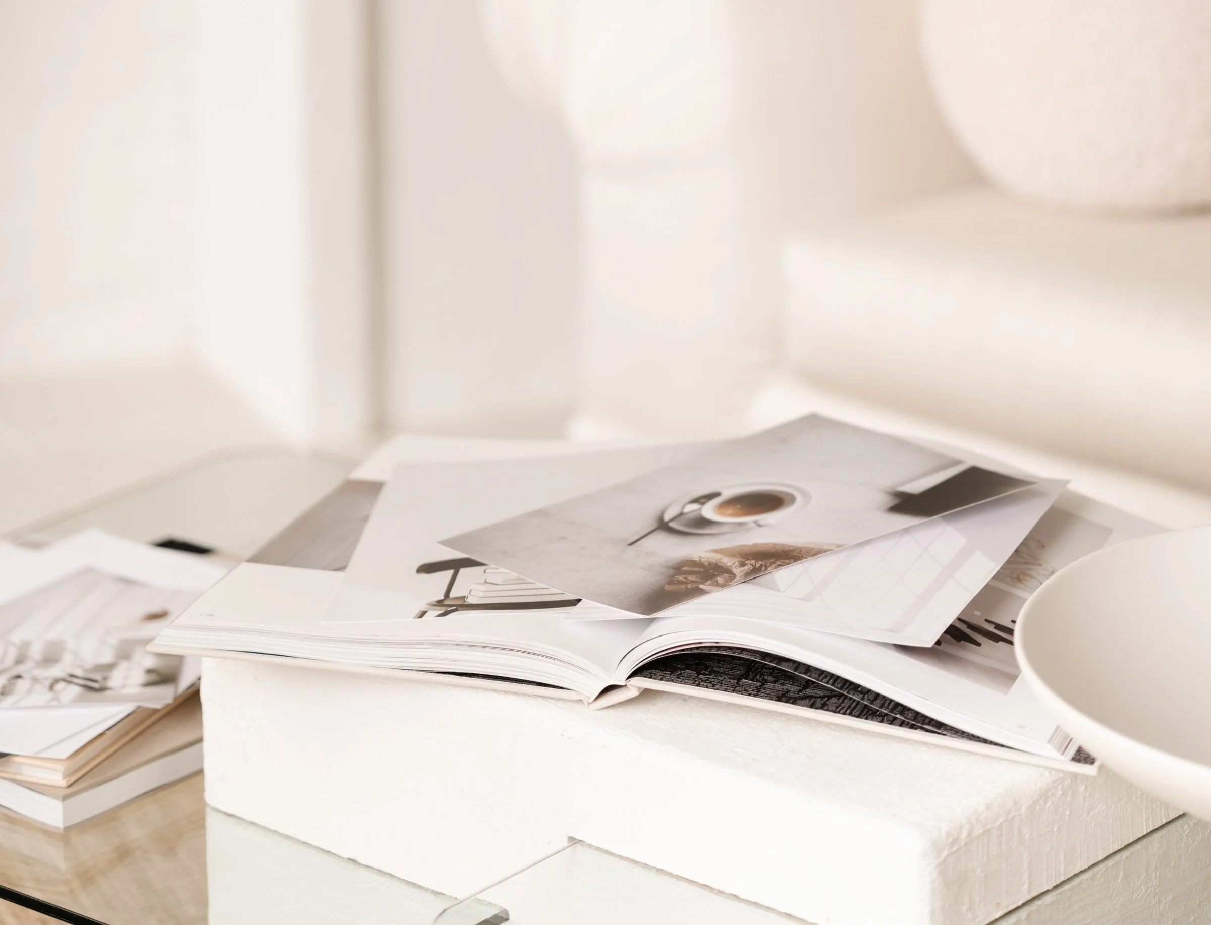 Assorted open magazines and papers spread out on a white table with a white background.
