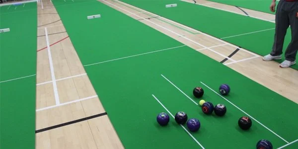 Bowling balls on a green lane in an indoor bowling alley.