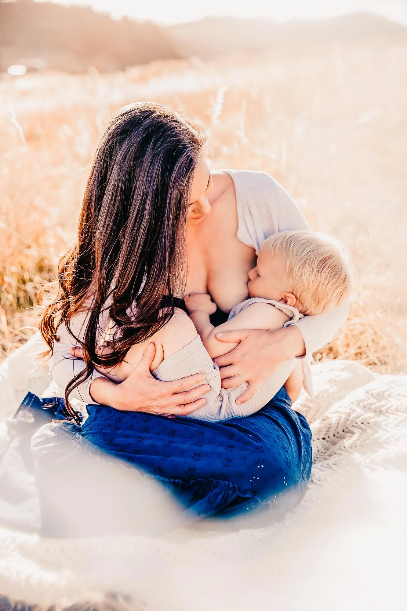 Mother breastfeeding baby outdoors in grassy field