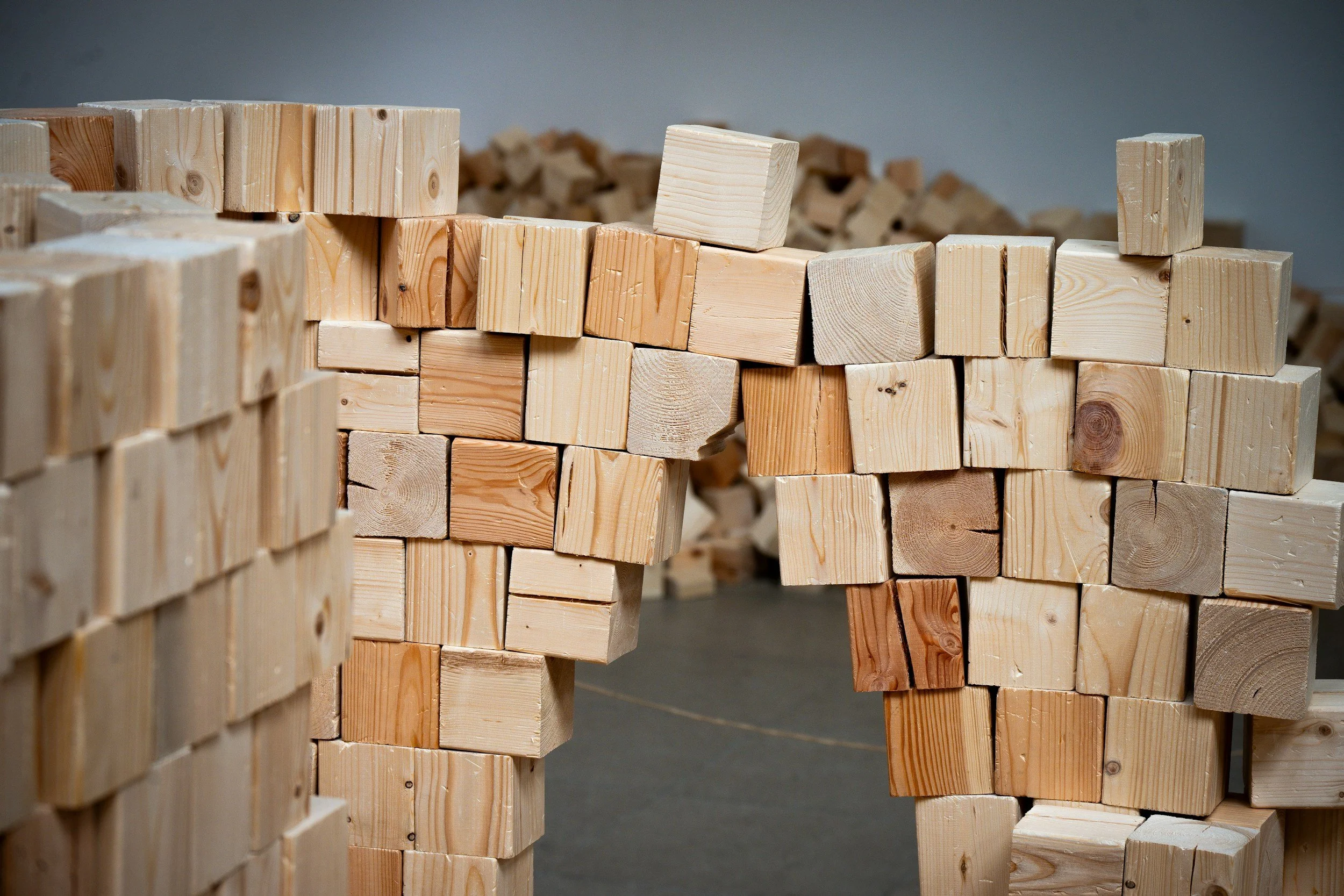 Stacks of unfinished wooden blocks arranged in a partially built structure.