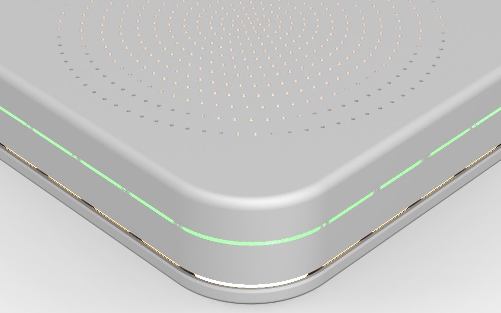Close-up of a modern electronic device, possibly a wireless charger or speaker, with a sleek metallic surface, small perforations on top, and a subtle green LED light strip along the edge.