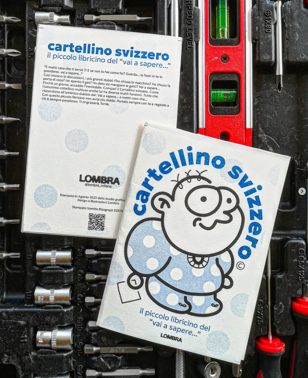 A small comic book titled "Cartellino Svizzero" with a cartoon character on the cover, placed on a toolbox along with tools and a spirit level.