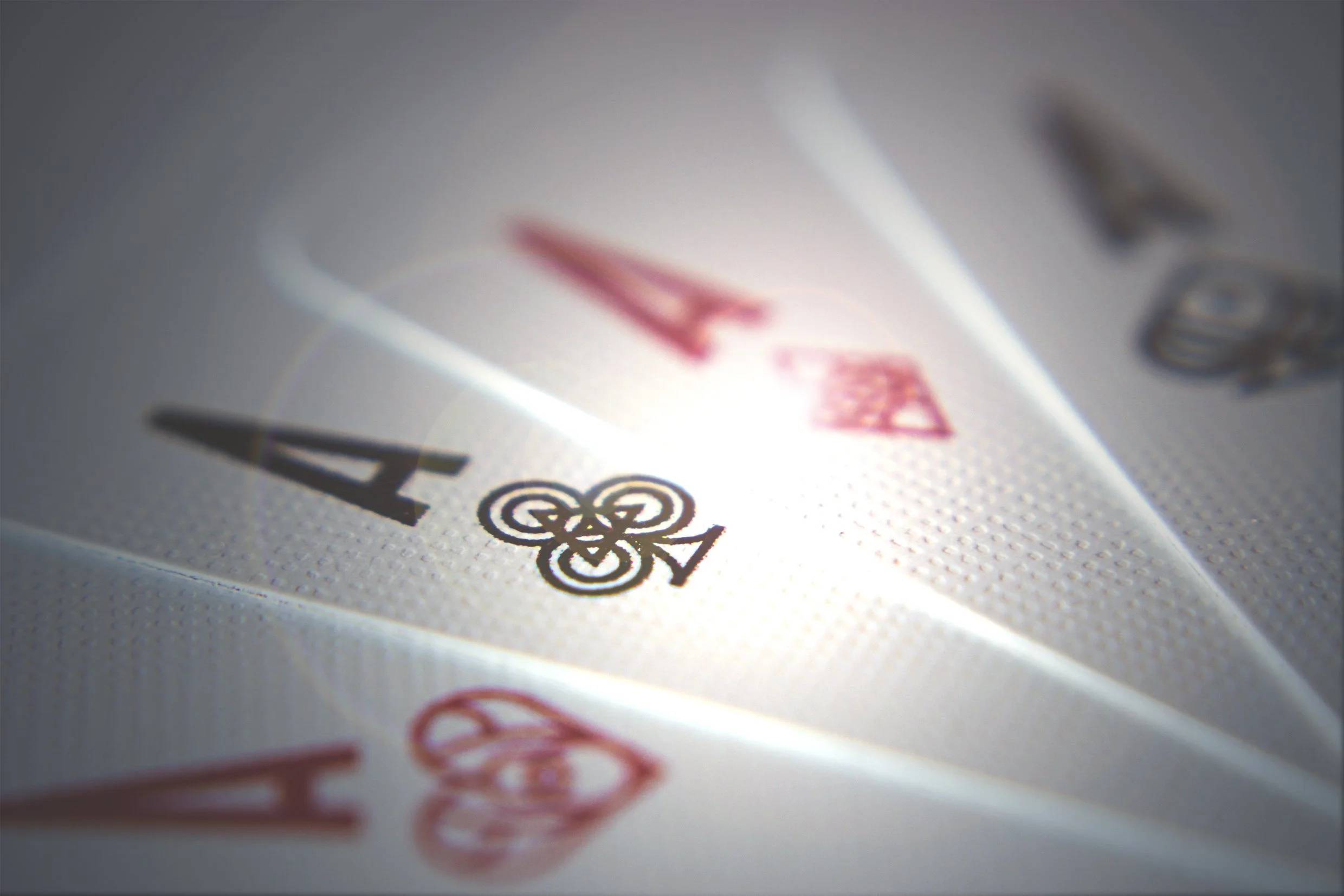 Close-up of a playing card, the Ace of Clubs, with the suit and rank visible, and a shadow cast on the surface.
