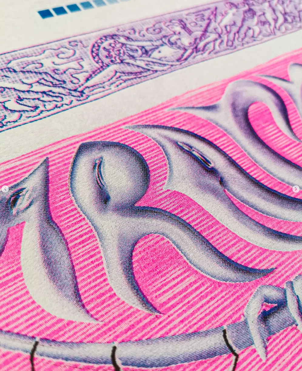 Close-up of a pink and purple banknote with intricate design details.