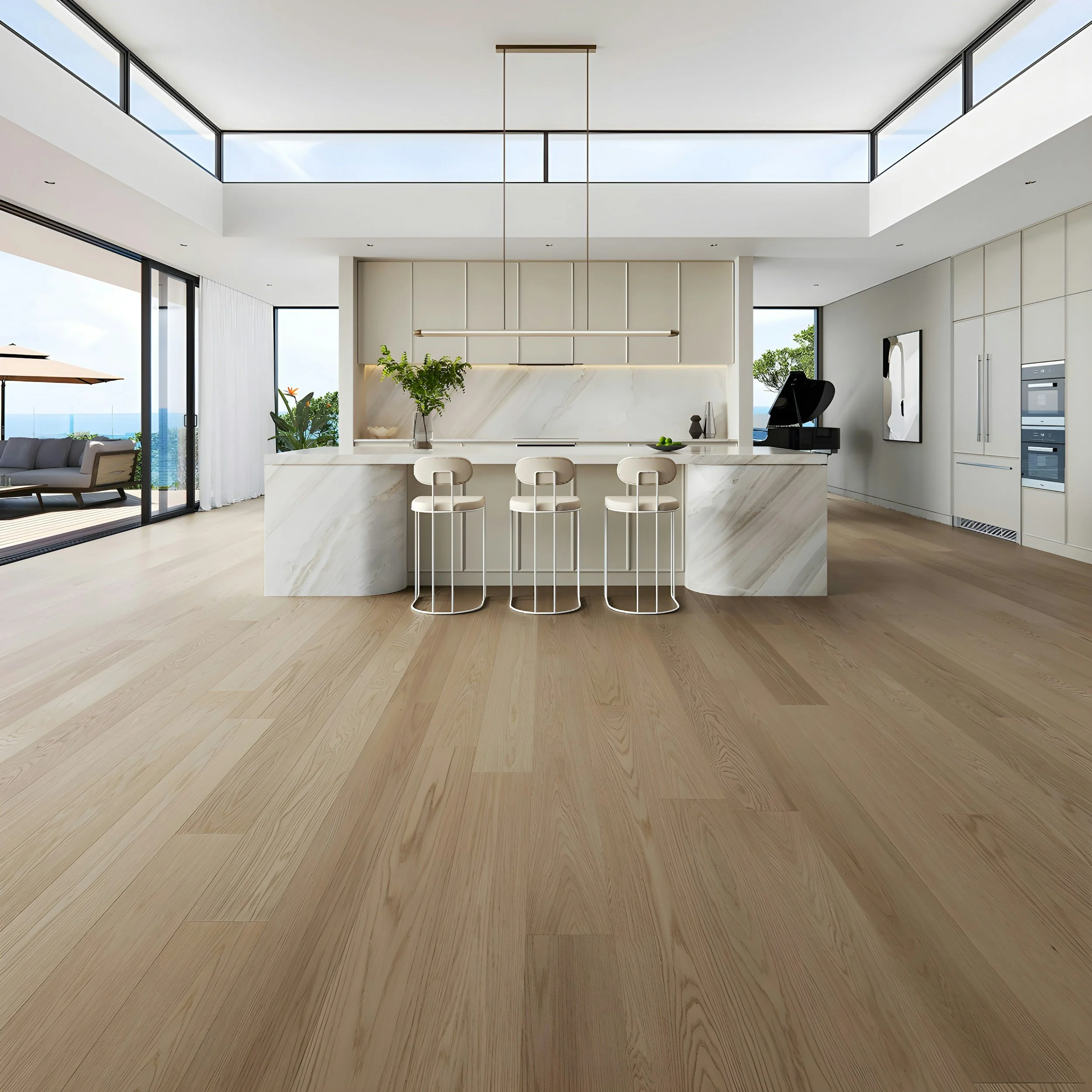Modern open-concept living space with a kitchen island, bar stools, a fireplace, and large glass sliding doors leading to an outdoor patio with outdoor furniture and an ocean view.