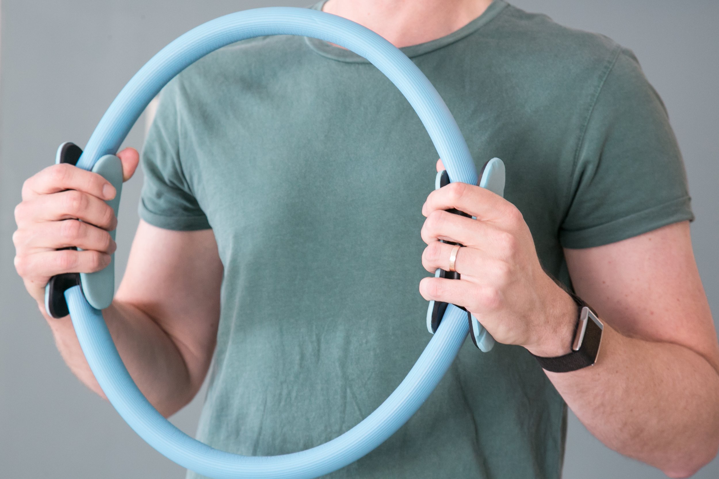Person holding a circular blue and black object with their hands, wearing a green t-shirt and a smartwatch on their left wrist.