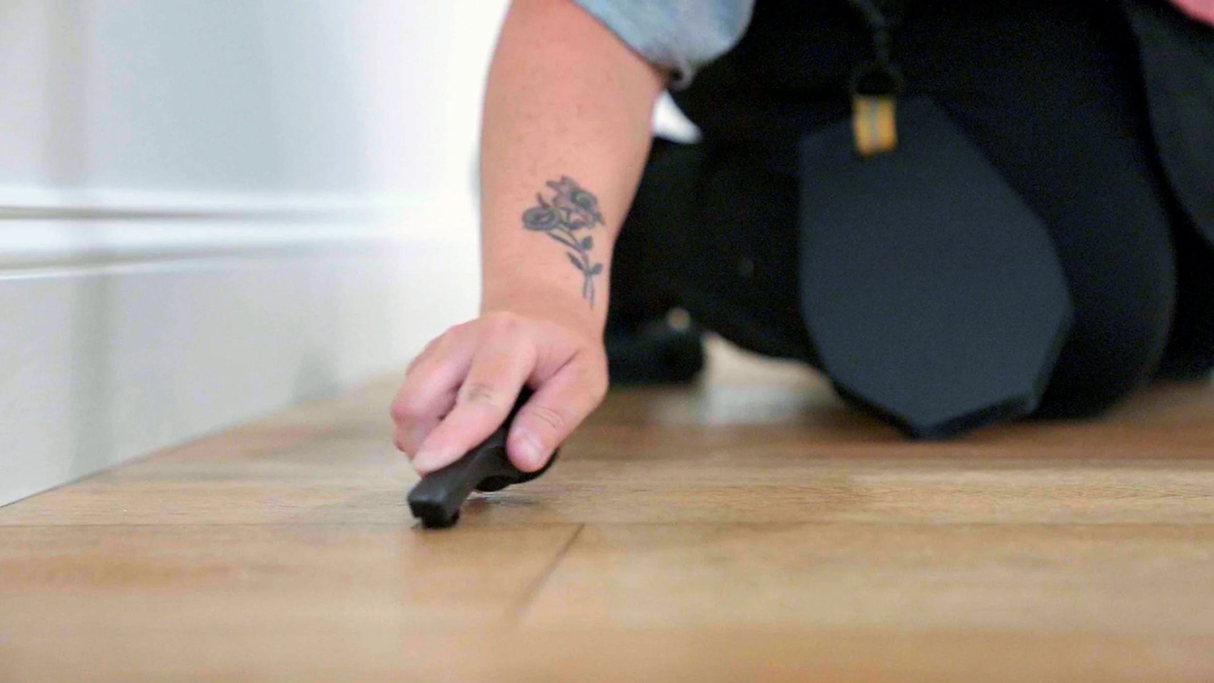 Cleaning technician at Harbor View Cleaning kneeling on a wooden floor, removing stains sand deep cleaning the floor.