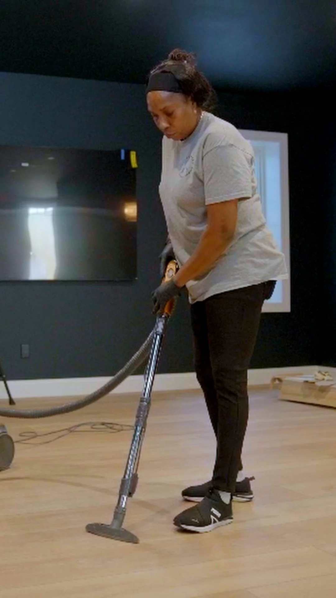 A person cleaning a wooden floor with a steam cleaner in a modern room.