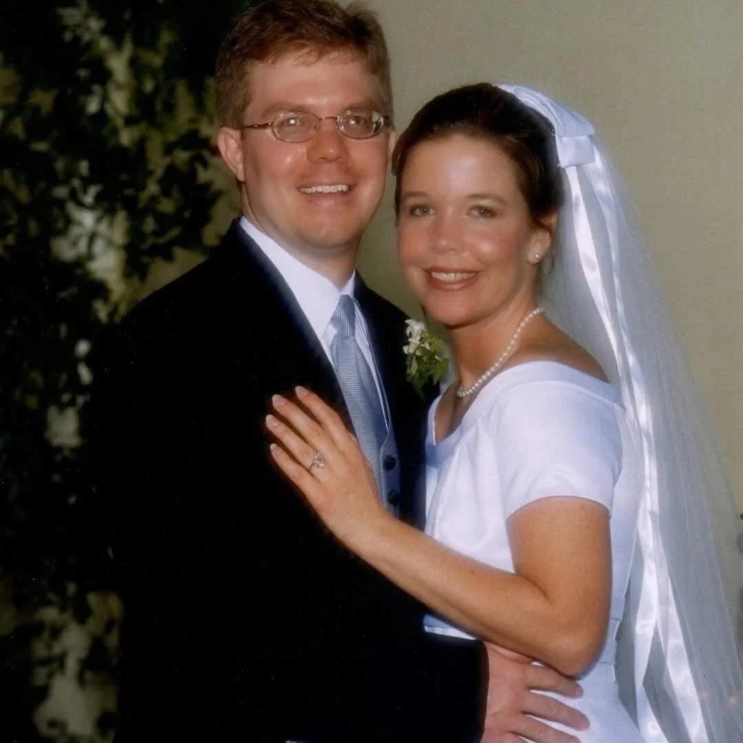 Kristie and Keith Sullivan on their wedding day, smiling together in wedding attire outdoors.