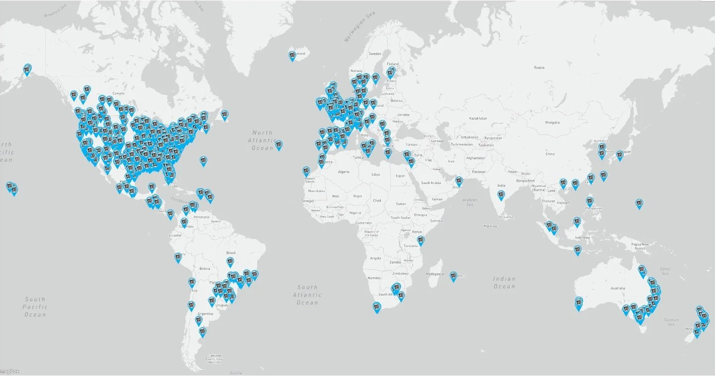 Global map showing numerous blue pins distributed across North America, Europe, Africa, Asia, and Australia, indicating location points or markers.