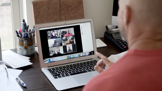Person participating in a video conference call on a laptop, with multiple people visible in the video grid.