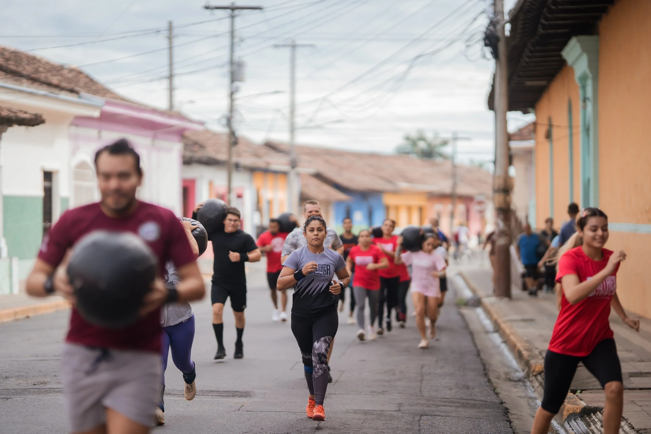 People participating in a street running event in a neighborhood with colorful houses, some runners are wearing athletic gear and running shoes.