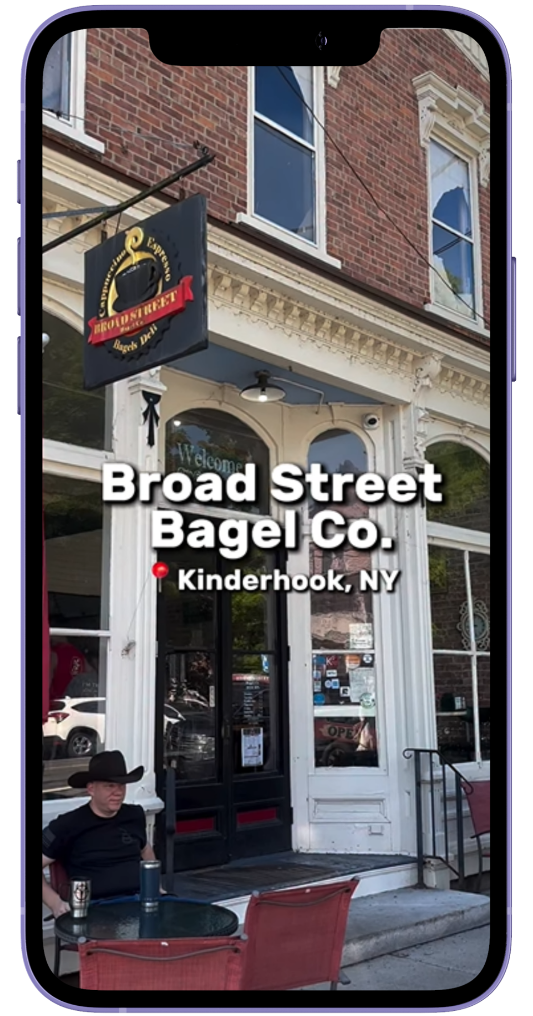Phone mockup of an Instagram reel for Broad Street Bagel Co, which has tall white front doors and red brick