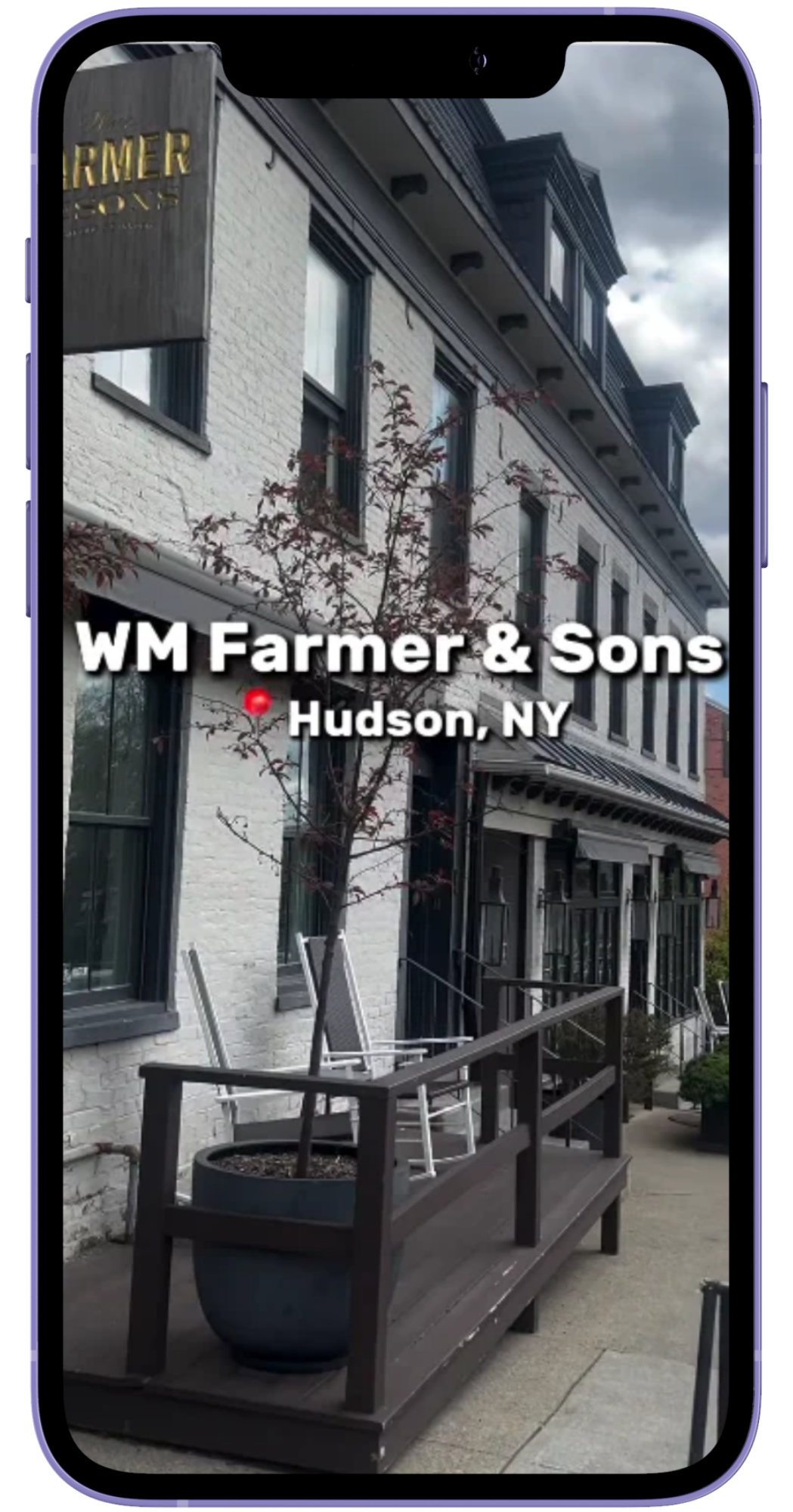 Phone mockup of an Instagram reel featuring WM Farmer and Sons, a historic white building in Hudson NY