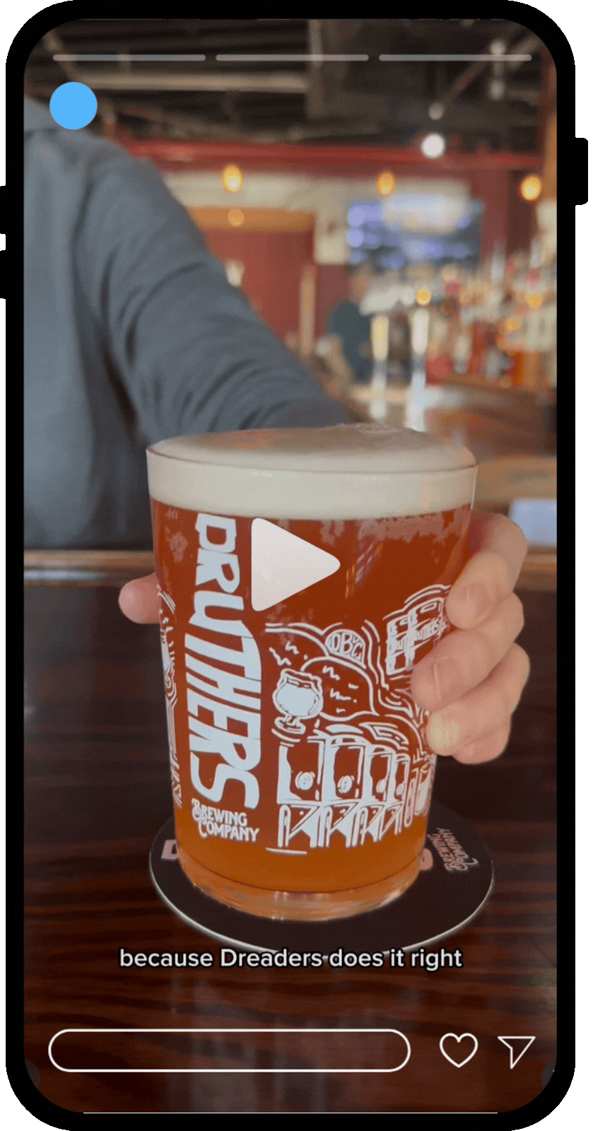 A person holding a pint of beer in a glass with "PATHFINDER" branding at a bar or brewery.