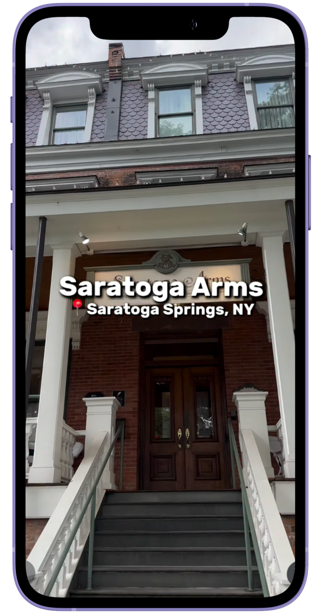 The photo shows the entrance to Saratoga Arms, a historic brick building with white columns, stairs, and a wooden door, located in Saratoga Springs, New York.